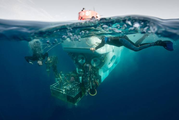 Atlantis crew members Patrick Neumann and Allison Heater assist in the recovery of Alvin following a test mission. They attach safety lines to support Alvin’s payload basket before it is lifted from the water. 